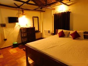 a bedroom with a bed with white sheets and red pillows at Gram Bangla Retreat in Kolkata