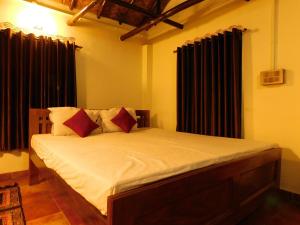 een slaapkamer met een bed met witte lakens en rode kussens bij Gram Bangla Retreat in Calcutta
