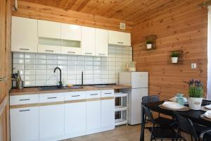 a kitchen with white cabinets and a dining table at Stecyk - Domki nad morzem, Trzęsacz in Trzęsacz