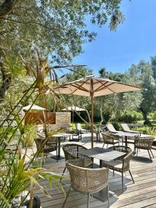 un patio con mesas, sillas y una sombrilla en Hôtel E Tre Stelle en Bonifacio