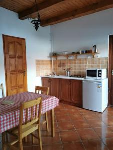 a kitchen with a table and a white refrigerator at Szenkeparti Vendégház in Penyige