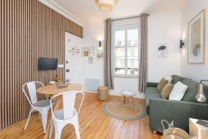 a living room with a green couch and a table at Studio front de mer en centre-ville de Cabourg in Cabourg