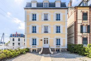 a large yellow building with stairs in front of it at Studio front de mer en centre-ville de Cabourg in Cabourg