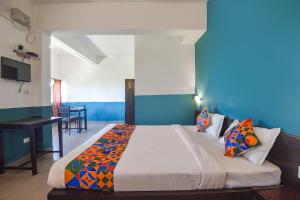 a bedroom with a large bed with blue walls at FabExpress Paradise Inn Panaji in Old Goa