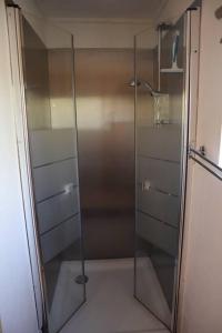 een douche met een glazen deur in de badkamer bij Basic Natuurhuisje Ommen/Beerze in Beerze