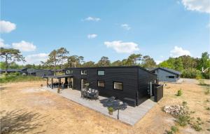 a black house on a field with a deck at Cozy Home In Nex With Kitchen in Snogebæk