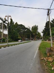 eine leere Straße mit einem Auto, das die Straße hinunterfährt in der Unterkunft Titi Panjang Apartment Lumut Sitiawan Manjung in Lumut