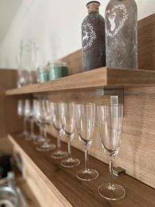 a row of wine glasses on a shelf with a bottle at Wolfgangsee Ferienappartement „Bergliebe“ in Strobl