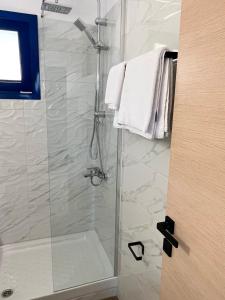 uma casa de banho com um chuveiro e uma porta de vidro em Akroyiali Resort em Vasiliki