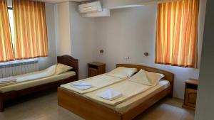 a bedroom with two beds and two windows at Guest House Katya in Nesebar