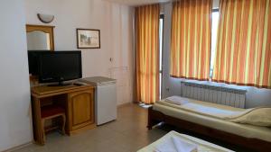 a hotel room with a bed and a television at Guest House Katya in Nesebar