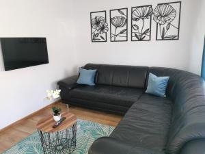 sala de estar con sofá de cuero negro y mesa en Under the Hill 2 en Bad Muskau