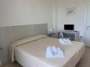 a bedroom with a bed with towels and a desk at Hotel Castelsardo Domus Beach in Castelsardo