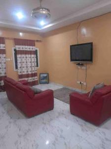 uma sala de estar com 2 sofás vermelhos e uma televisão de ecrã plano em Comfy & cozy 2 bedroom apartment, entire unit! em Banjul