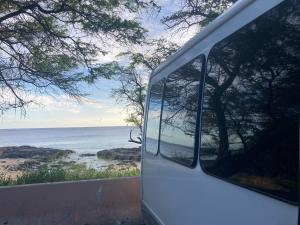 une camionnette blanche garée sur le côté d'une plage dans l'établissement Oahu Camper Adventures, à Kailua