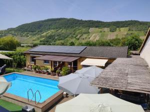 a villa with a swimming pool and umbrellas at Moselferienweingut Schaefer in Wintrich