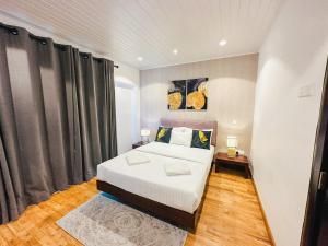 um quarto com uma grande cama branca e 2 candeeiros em The Edge Luxury Apartment em Nuwara Eliya