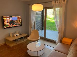 a living room with a couch and a sliding glass door at Apartament Bryza - Szczęśliwa Dziewiątka in Jurata