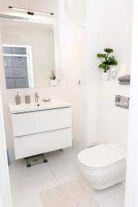 a white bathroom with a toilet and a sink at Chill Apartments Jurajska Plaza Kielce Targi in Kielce