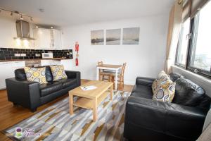 una sala de estar con 2 sofás de cuero negro y una mesa. en Thistle Apartments - Rose Apartment en Aberdeen