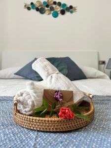 La Perla Marina House في شيافاري: سلة مع المناشف والورود على السرير