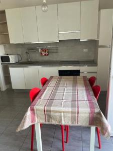 une cuisine avec une table, des chaises rouges et des armoires blanches dans l'établissement Monolocale al porto, à Fano