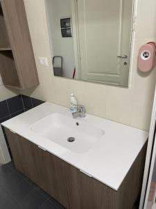 La salle de bains est pourvue d'un lavabo blanc et d'un miroir. dans l'établissement Monolocale al porto, à Fano