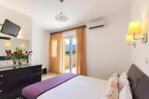 a bedroom with a bed and a television and a balcony at Rani Apartments in Chrysi Ammoudia