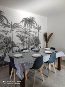 uma sala de jantar com uma mesa com cadeiras e um mural de palmeiras em Les Caze de la Mer Cassée em Saint-Philippe