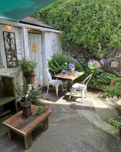 un patio con mesa, sillas y flores en The Artist's Retreat, en Calstock