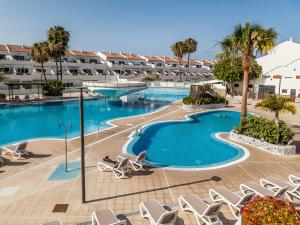 a swimming pool with chairs and a resort at BLUE WATERS Apartment with heated pool in Costa Del Silencio