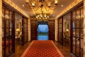 a hallway with a chandelier and a red rug at The Westbury Palace in Nuwara Eliya