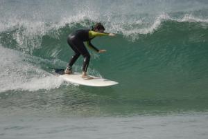 a man riding a wave on a surfboard in the ocean at Casa Carmen Pedeboi in Viveiro