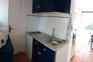 T1 rez de jardin avec grande terrasse – St Aygulf في فريجوس: مطبخ صغير مع دواليب زرقاء ومغسلة