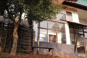 a building with a tree in front of it at Coorg Nature Breeze Homestay in Madikeri