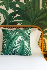 - un lit avec un oreiller et un mur vert verdoyant dans l'établissement Hôtel La Piscine, au Lavandou