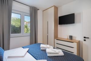 Un dormitorio con una cama azul con toallas. en A&D Deluxe apartments Dani with swimming pool, en Promajna