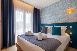 - une chambre avec un grand lit aux murs bleus dans l'établissement Hôtel La Piscine, au Lavandou