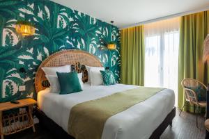 a bedroom with a large bed with a green wall at Hôtel La Piscine in Le Lavandou