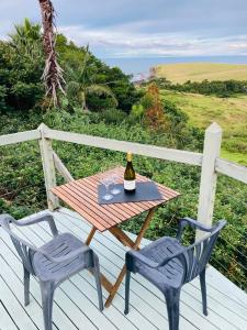 a table and two chairs on a deck with a bottle of wine at Wave n' Sea in Kiama