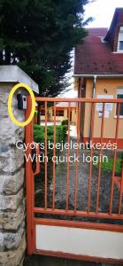 a gate with a yellow circle on it next to a house at Strigonia Apartman in Esztergom