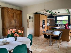 una cocina con 2 mesas y sillas y una mesa con flores. en Agréable chambres d’hôte, en Parence