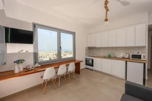 een keuken met witte kasten en een aanrecht met stoelen bij Aerial Apartment in Karterados
