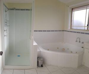 a white bathroom with a tub and a shower at Spacious Home in West Moonah, Hobart in Moonah
