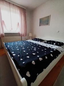 - une chambre avec un lit et une couverture noire avec des coeurs blancs dans l'établissement Mia, à Tomislavgrad