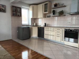 une cuisine avec des armoires blanches et des appareils noirs dans l'établissement Mia, à Tomislavgrad