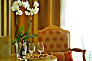 a table with two wine glasses and a vase with flowers at Hotel Cascais Miragem Health & Spa in Cascais