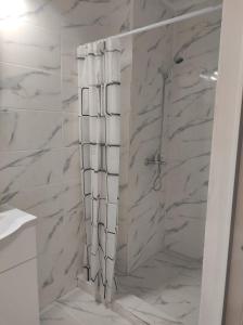 a bathroom with a shower with white marble walls at Apartament Diaconu Coresi (Piata Sfatului) in Braşov