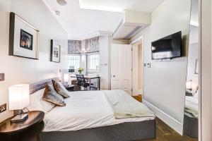 een slaapkamer met een bed, een bureau en een televisie bij The One South Kensington in Londen