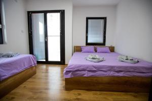 two beds in a room with purple sheets and windows at Pejik apartment in Ohrid
